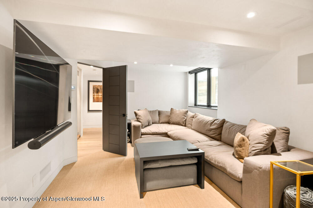 Living room with a beige sectional sofa, wall-mounted TV, and light wood floors.