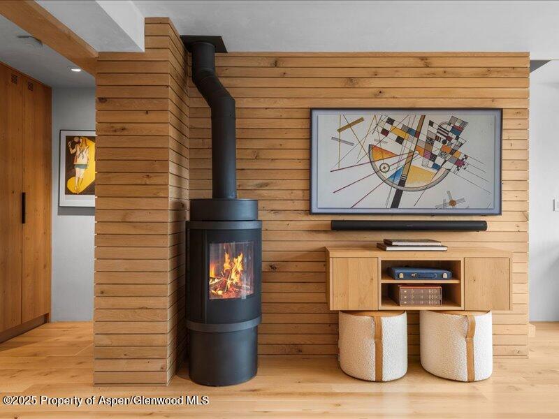 Living room with a black wood-burning stove, wood-paneled walls, and framed abstract artwork.