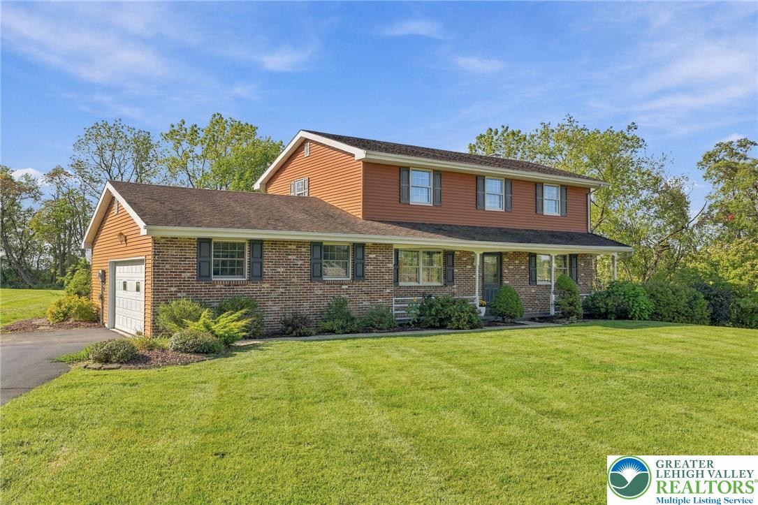 Two-story brick-and-siding home with an attached garage and broad front lawn.