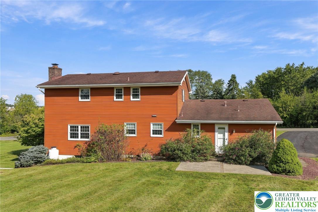 Orange two-story house with an attached wing, landscaped shrubs, green lawn, and paved driveway.