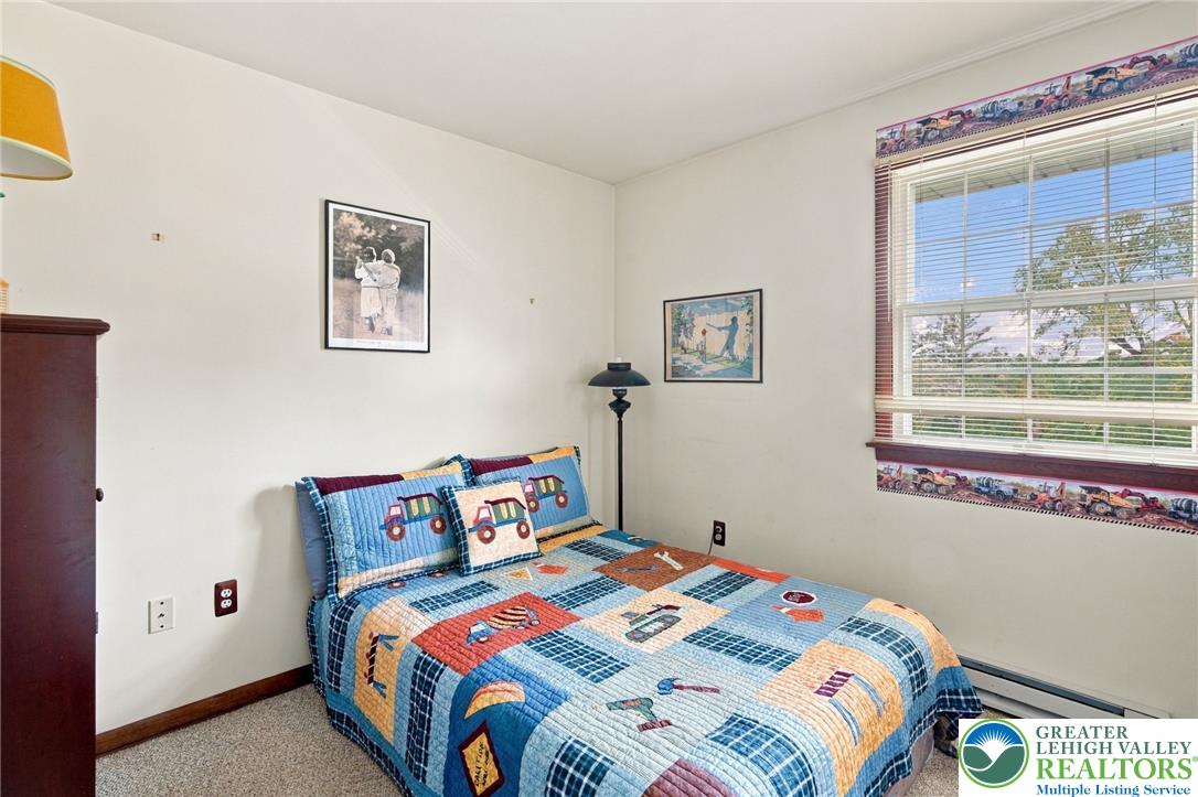Bedroom with a colorful vehicle-print quilt, matching pillows, and a large window.