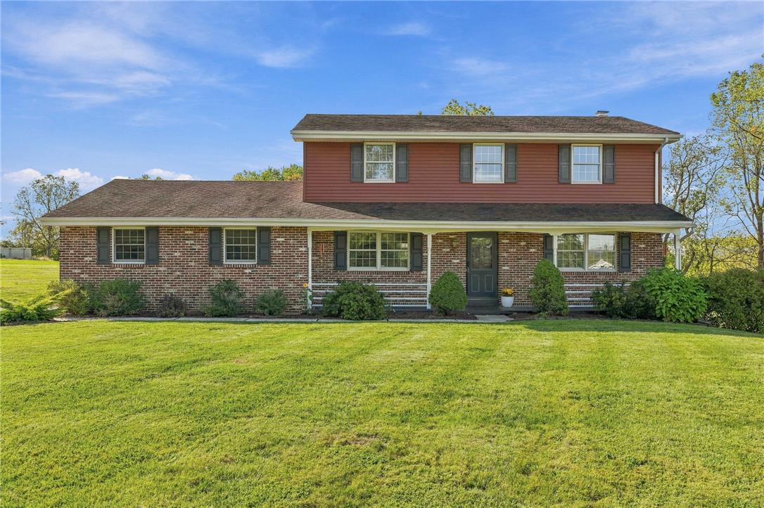 Two-story brick and red-sided house with a covered porch and broad lawn.
