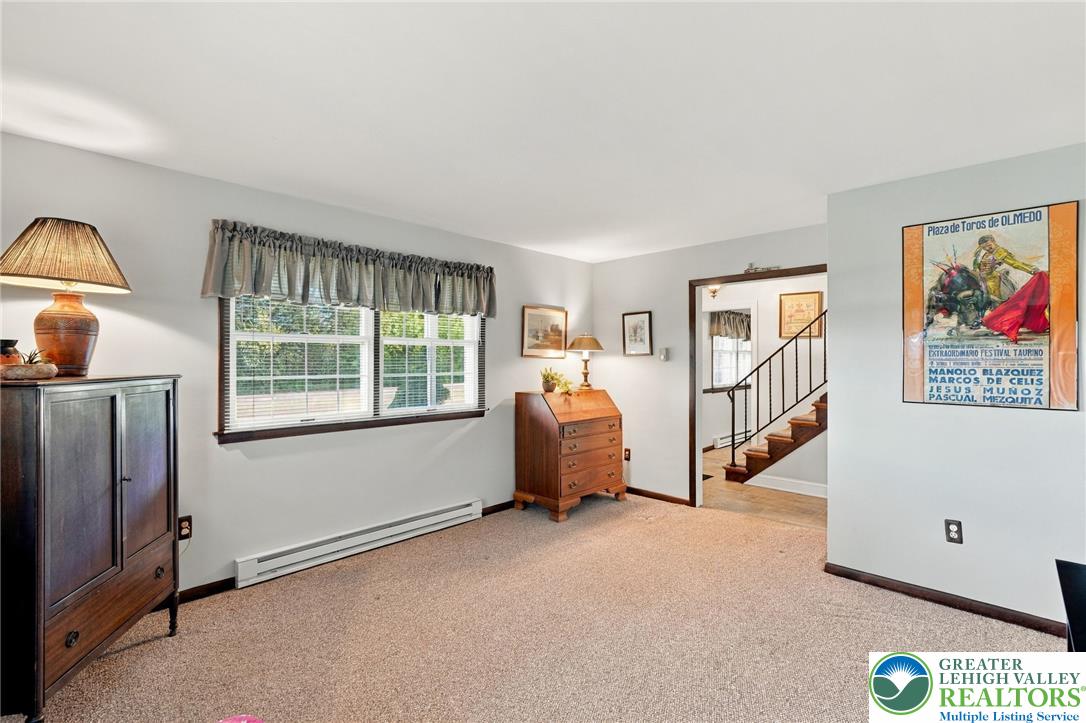 Carpeted room with two windows, dark wood furniture, and a doorway opening onto a staircase.
