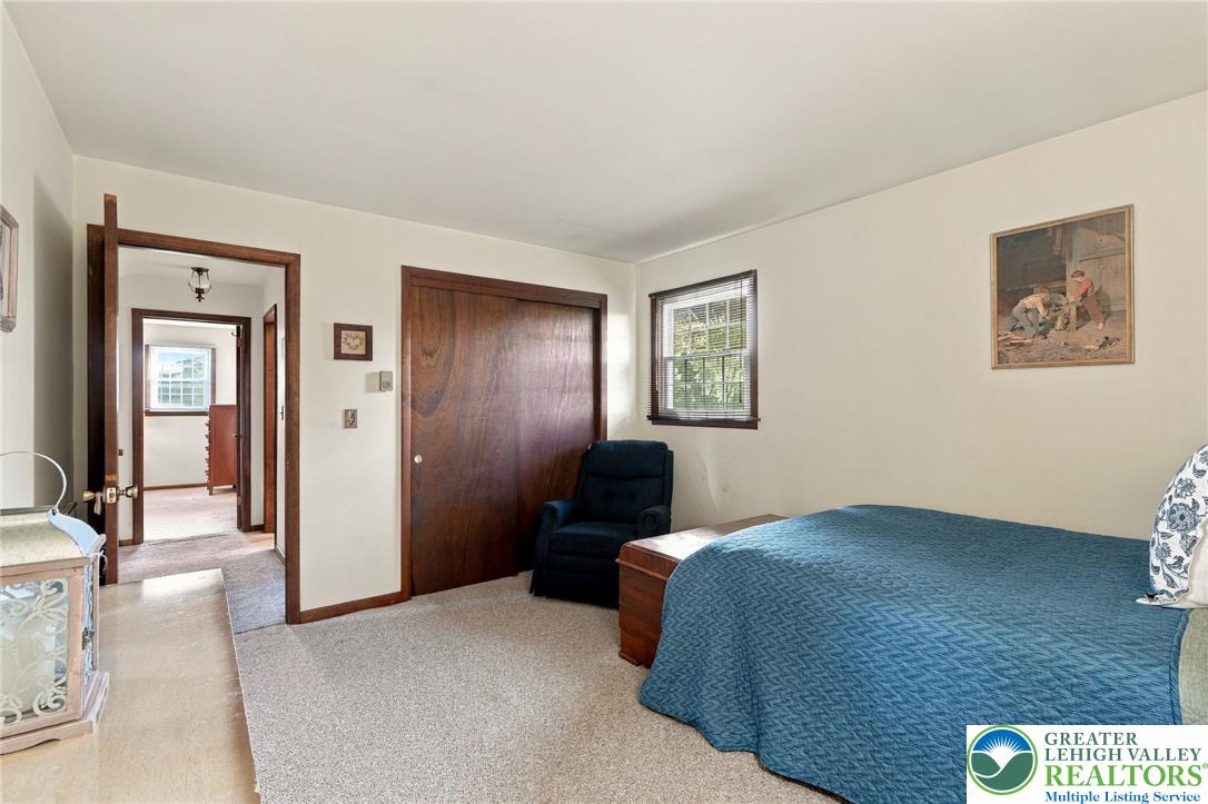 Bedroom with a blue quilted bed, dark wood trim, and sliding closet doors.