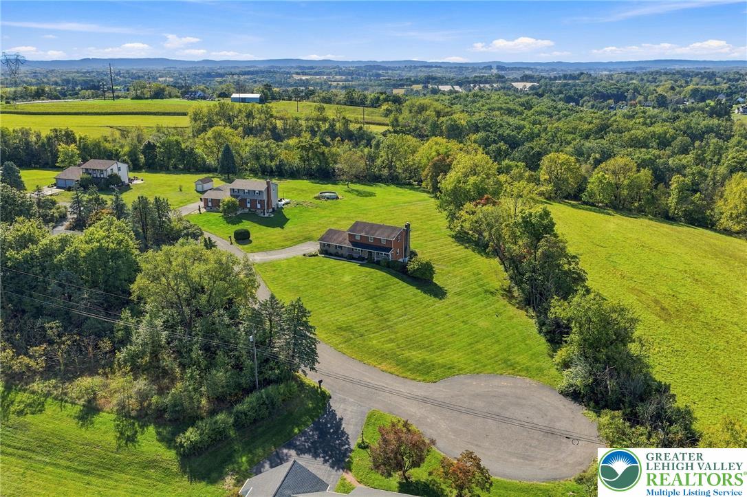 Aerial view of homes on expansive green lots surrounded by wooded countryside.
