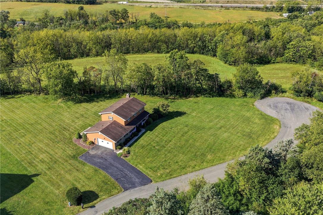 Aerial view of a two-story home surrounded by broad lawns, trees, and open fields.