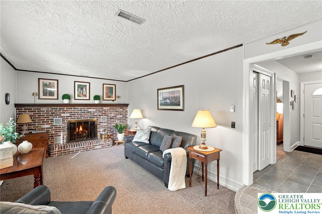 Living room with a lit brick fireplace and gray leather sofa.