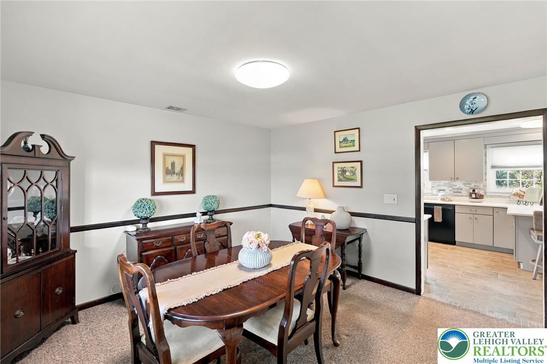 Furnished dining room with a dark wood table and china cabinet, opening to a bright kitchen.