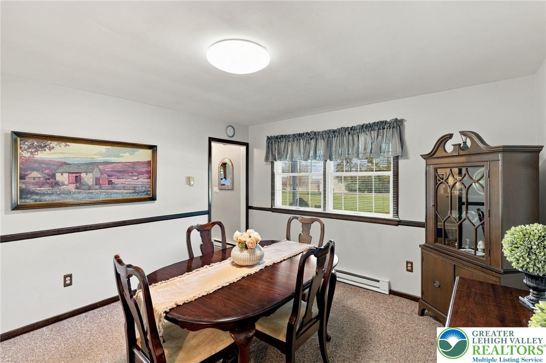 Dining room with a dark wood table, china cabinet, and window overlooking the lawn.