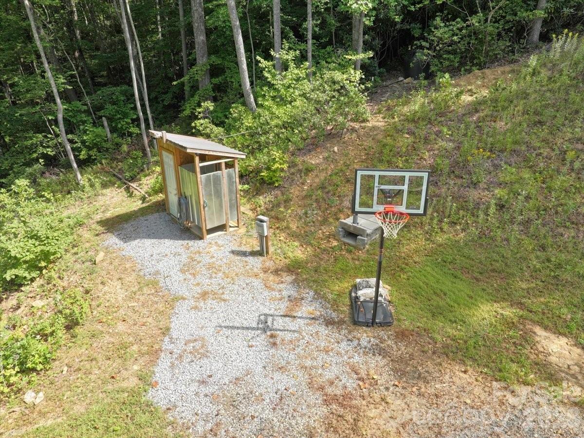 Aerial view of a wooded clearing with a small shed and basketball hoop.