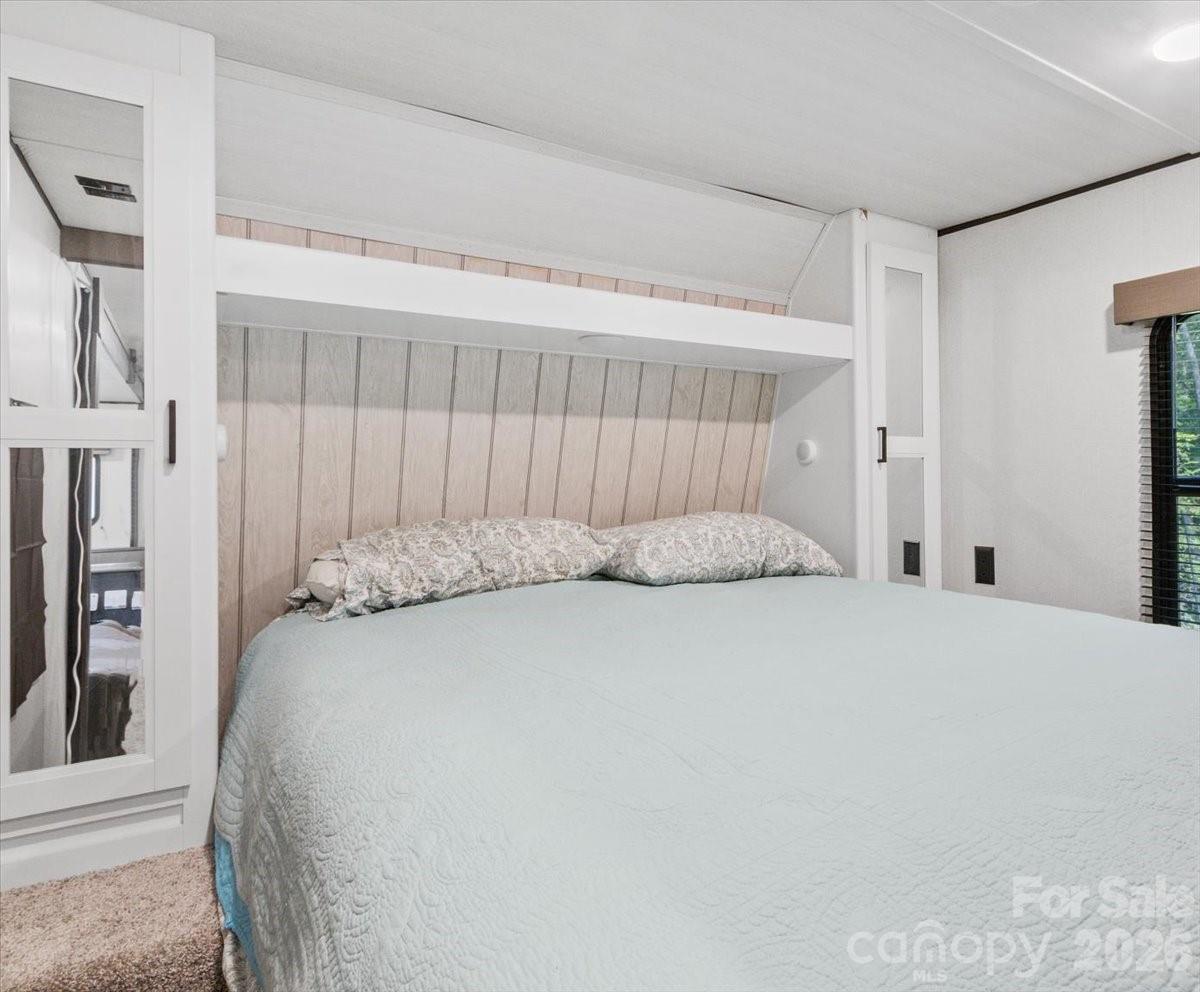 Bedroom with a large pale blue quilted bed framed by white built-in cabinetry.