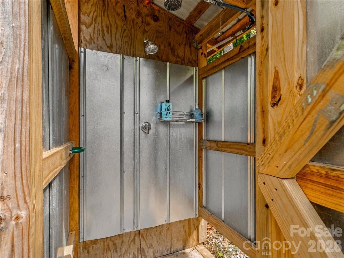 Outdoor shower with silver metal panels and exposed wooden framing.