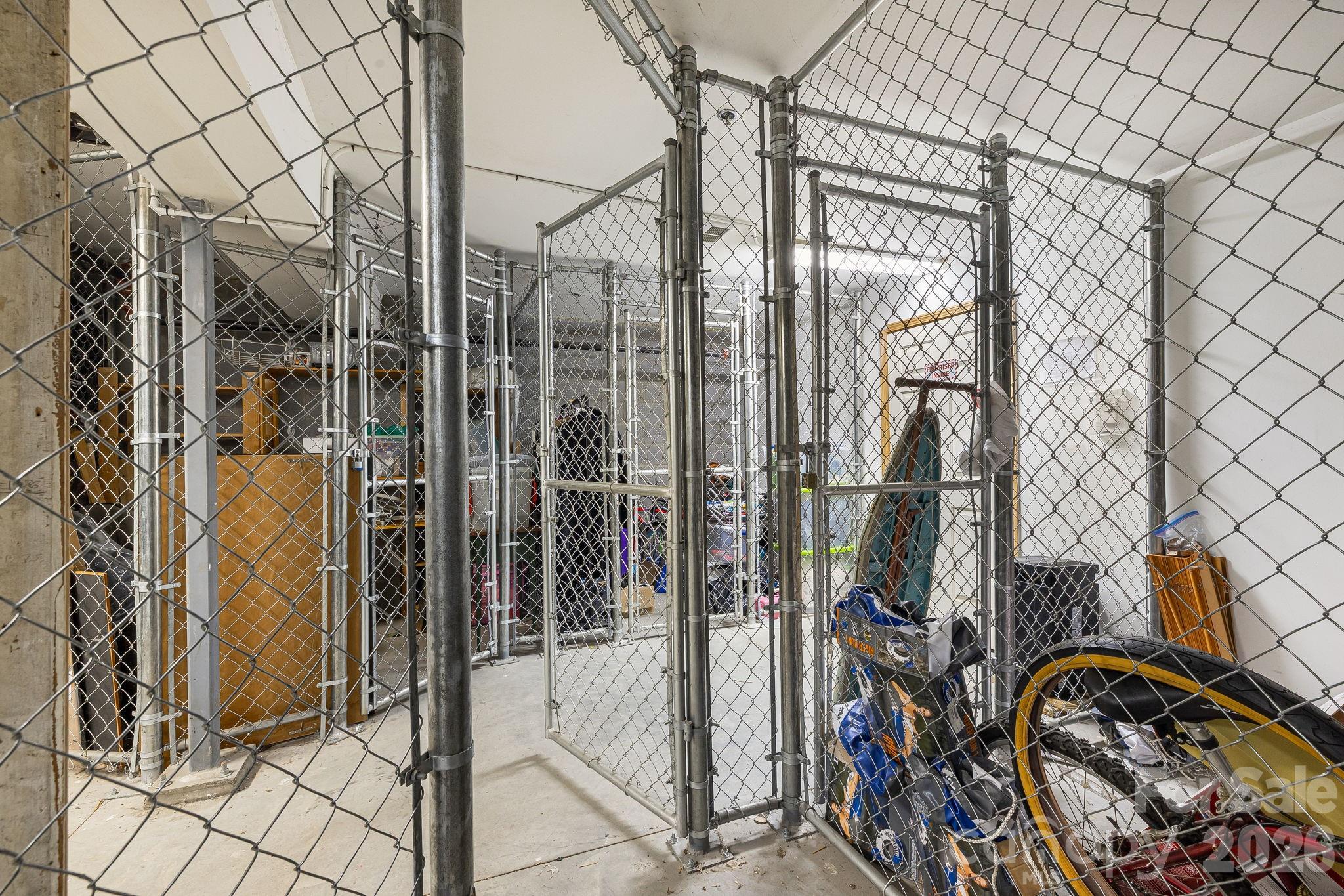 Interior storage area with chain-link cages and bicycles stored behind the fencing.