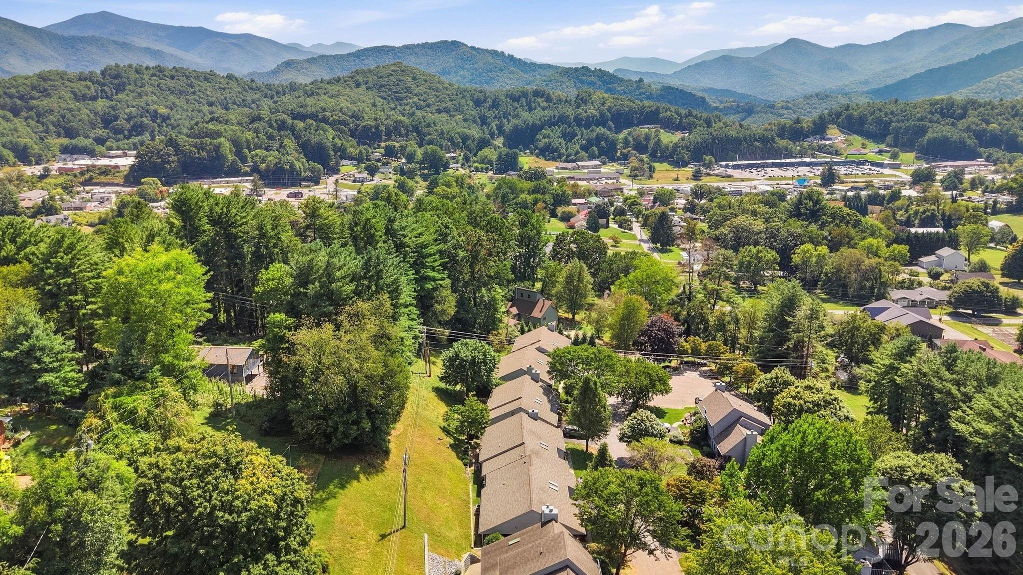 Aerial view of a wooded neighborhood and commercial area with mountain ridges in the distance.