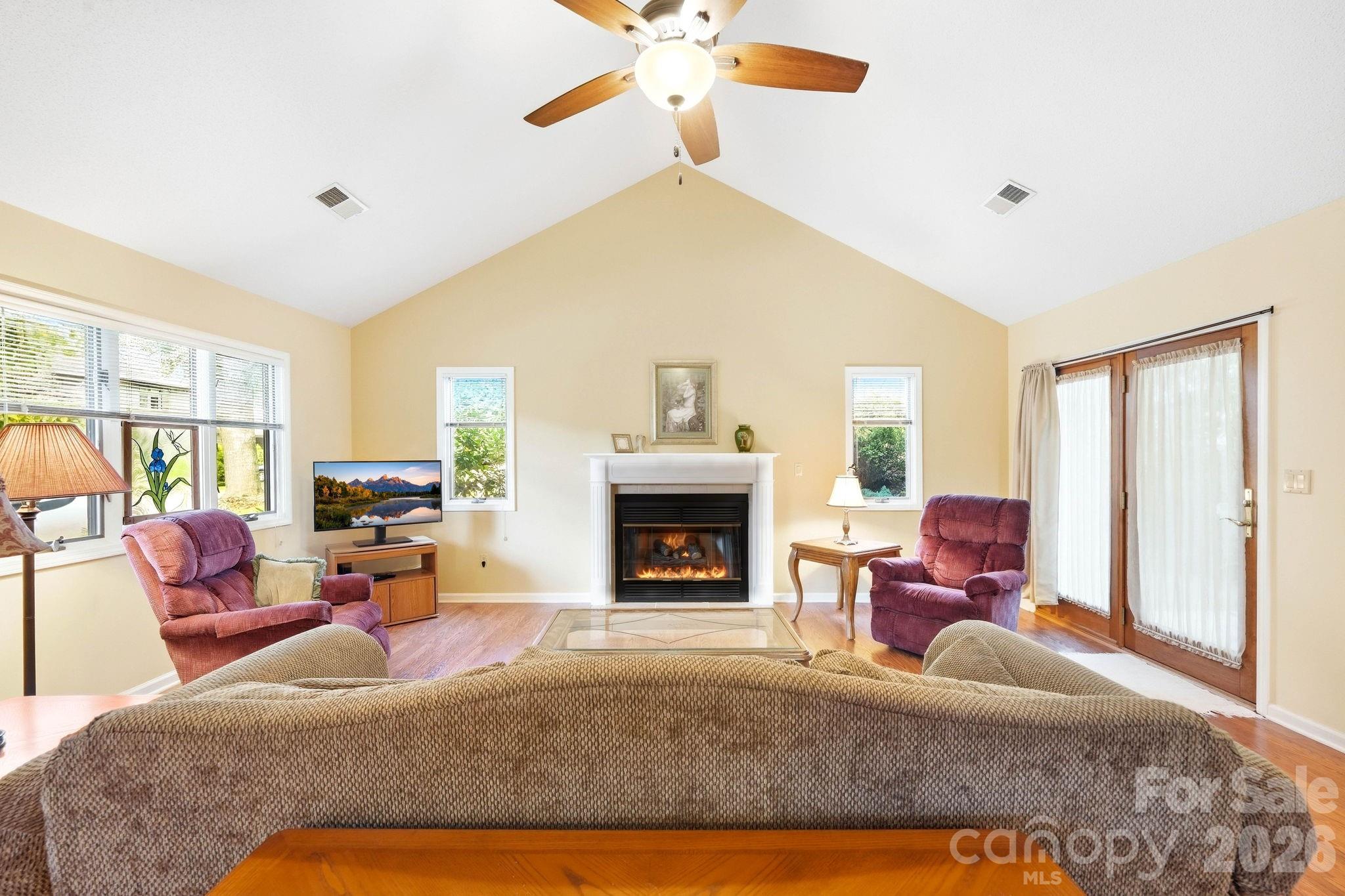 Living room with a vaulted ceiling, gas fireplace, and glass doors.