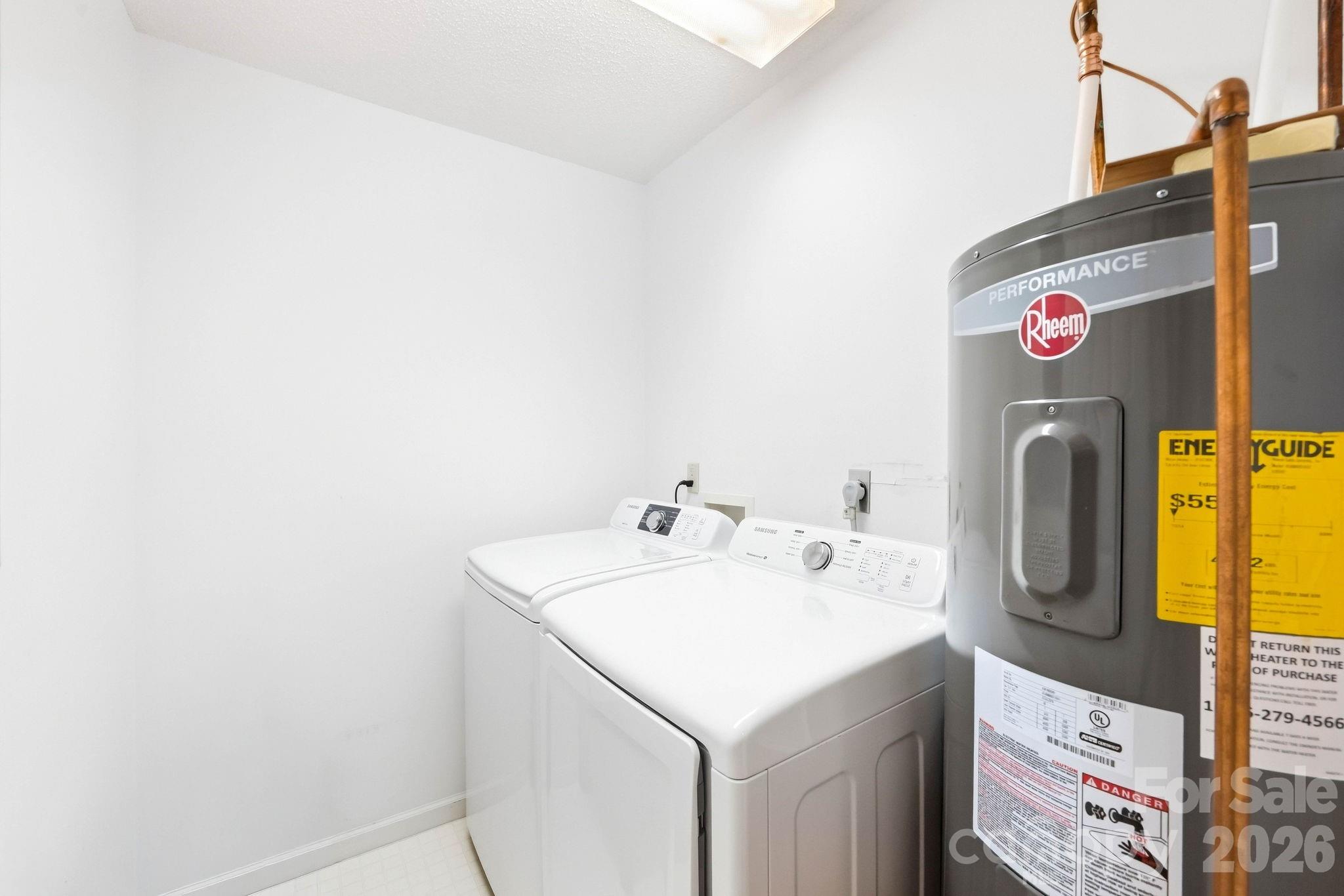 Laundry room with a washer and dryer beside a large Rheem water heater.