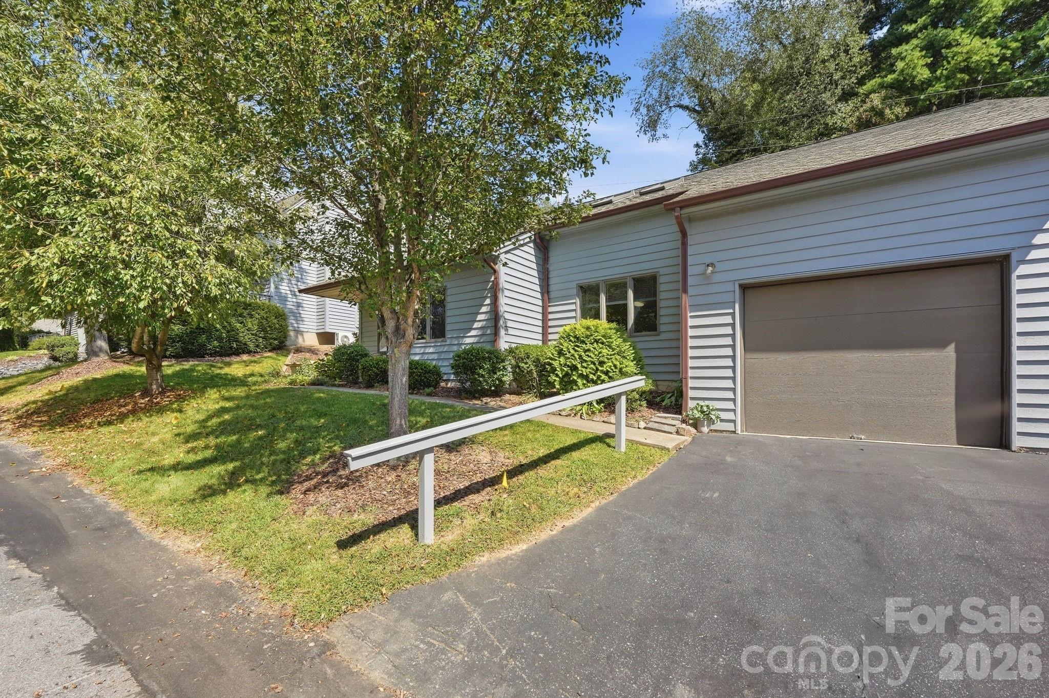 Single-story home with a large garage, landscaped lawn, and white-railed access ramp.