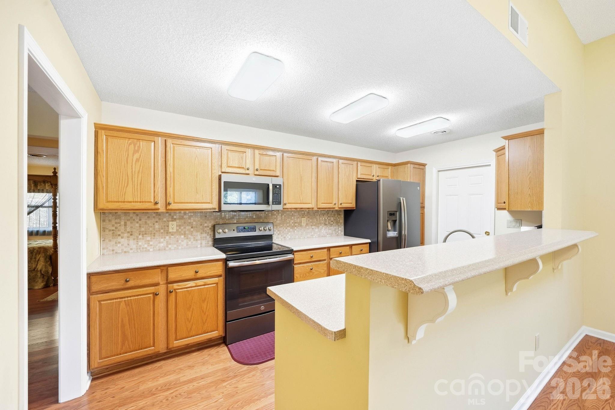 Kitchen with honey-colored cabinets, stainless steel appliances, and a raised breakfast bar.