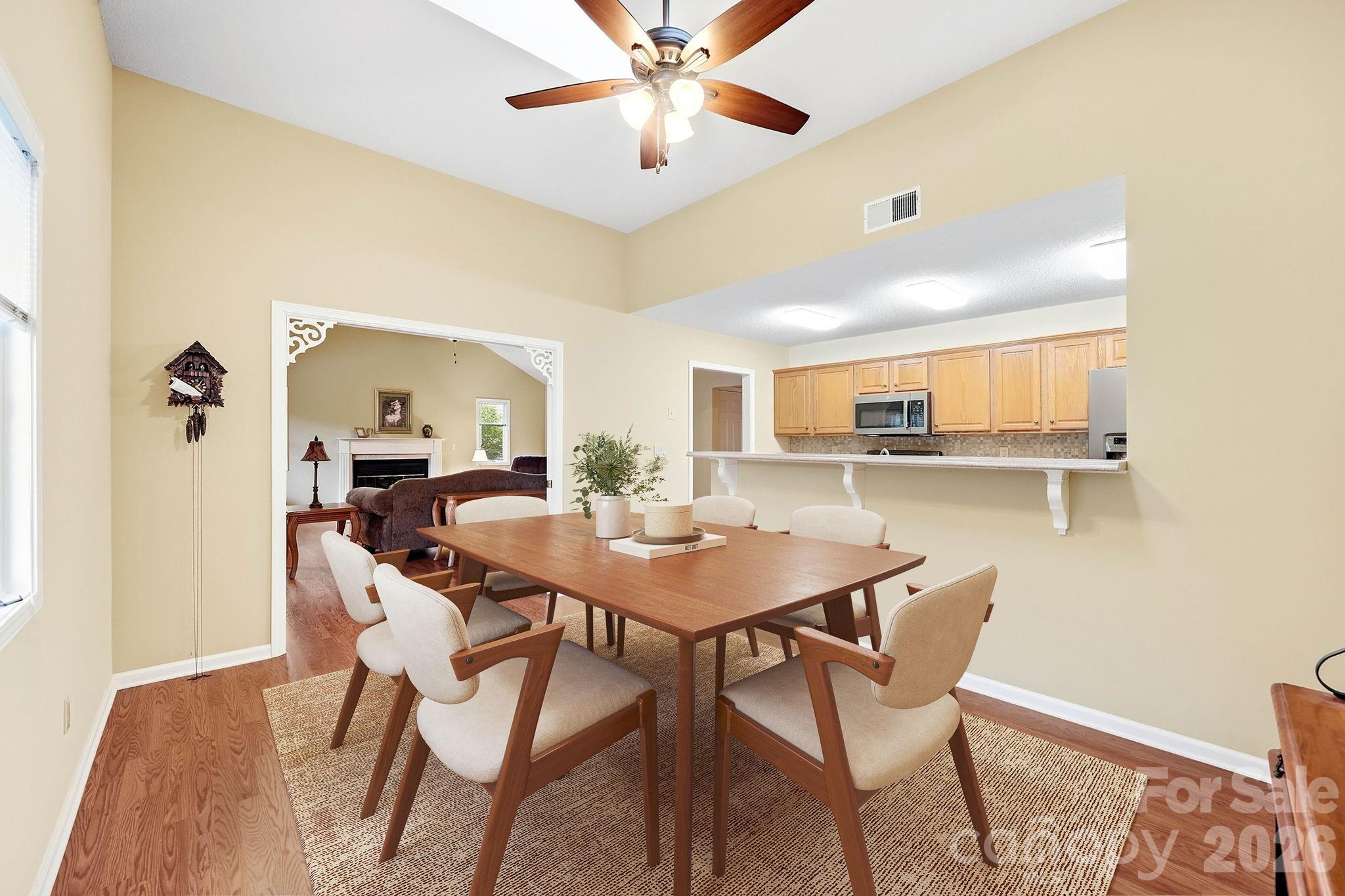 Dining room with a wood table, upholstered chairs, and an open breakfast bar to the kitchen.