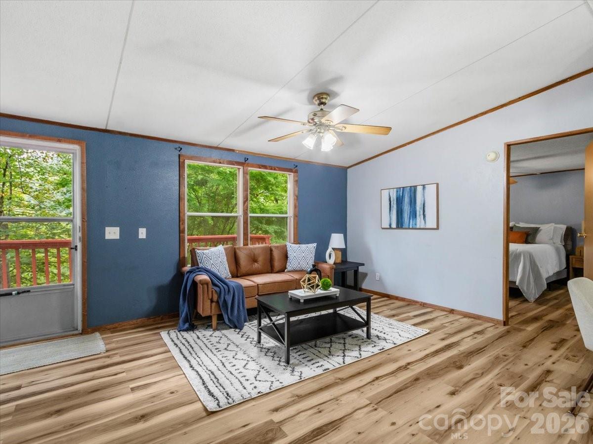 Living room with a brown sofa, blue accent wall, and windows overlooking trees and a deck.