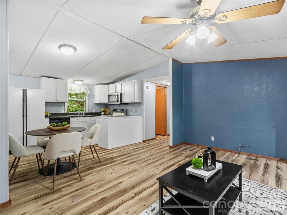 Open-plan kitchen and dining area with white cabinets, blue walls, and wood-look flooring.