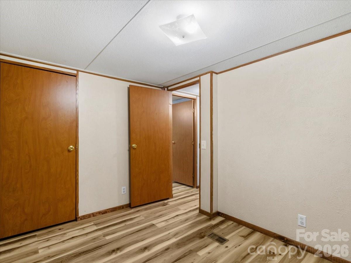 Empty room with wood-look flooring, cream walls, and wooden closet doors.