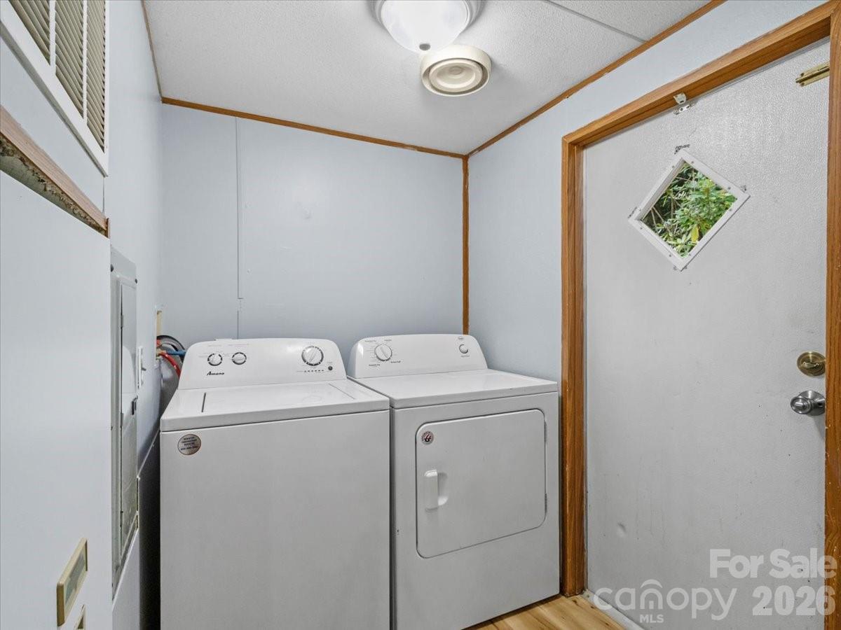 Laundry room with a white washer and dryer beside a door with a diamond-shaped window.