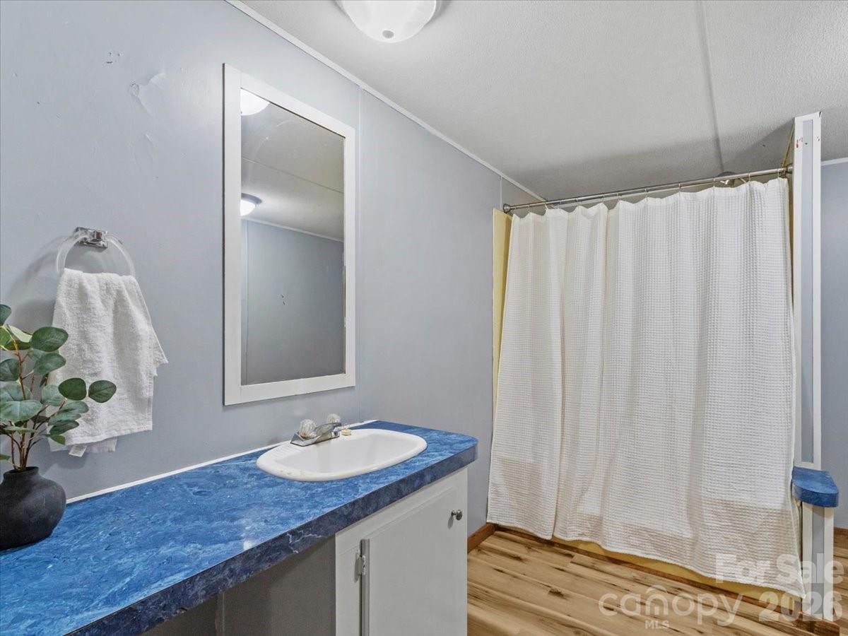 Bathroom vanity with a vivid blue countertop beside a shower with a white curtain.