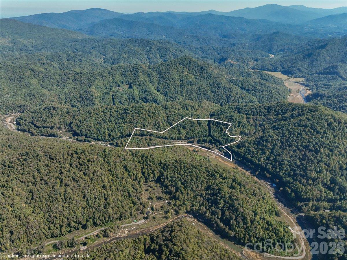 Aerial view of a wooded mountain parcel outlined in white, with a river and mountain ridges nearby.