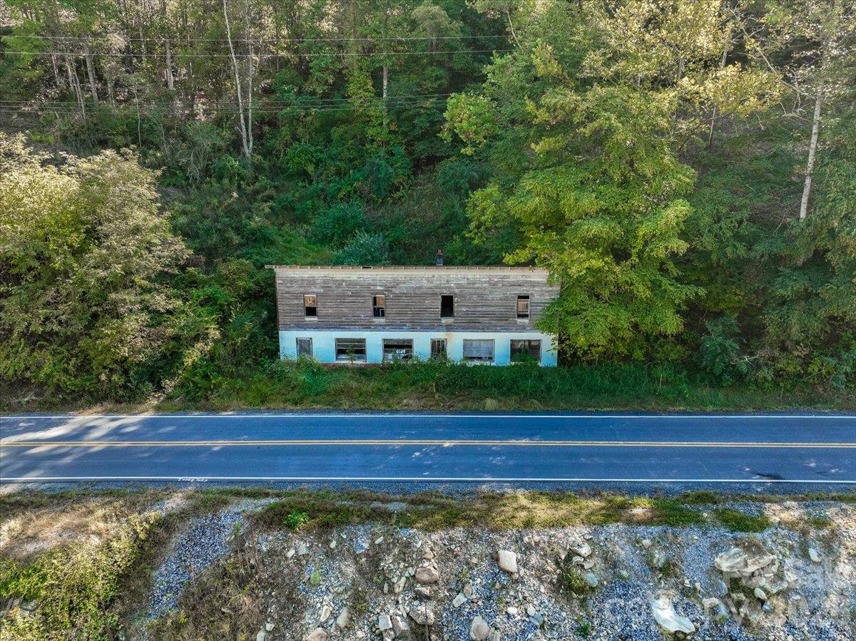 Roadside two-story building with weathered wood siding, surrounded by trees beside a highway.