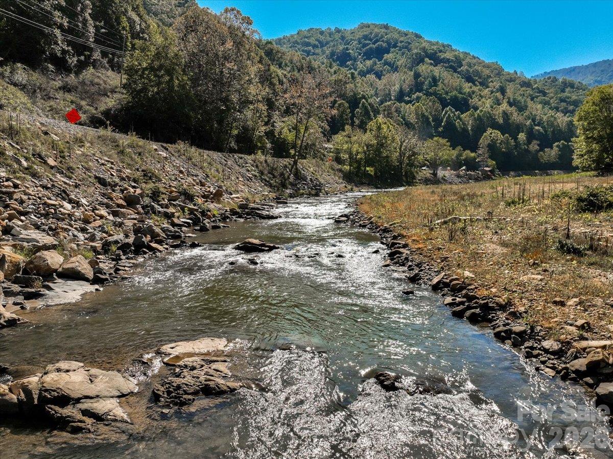 Rocky stream through a mountain property, bordered by autumn trees and grassy banks.