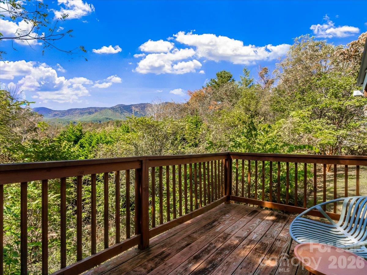 Wooden deck overlooking wooded hills and a distant mountain ridge.