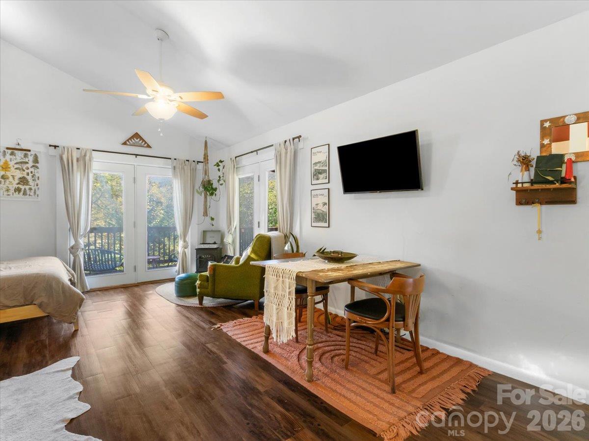 Furnished living area with a green armchair, dining table, and glass doors overlooking trees.