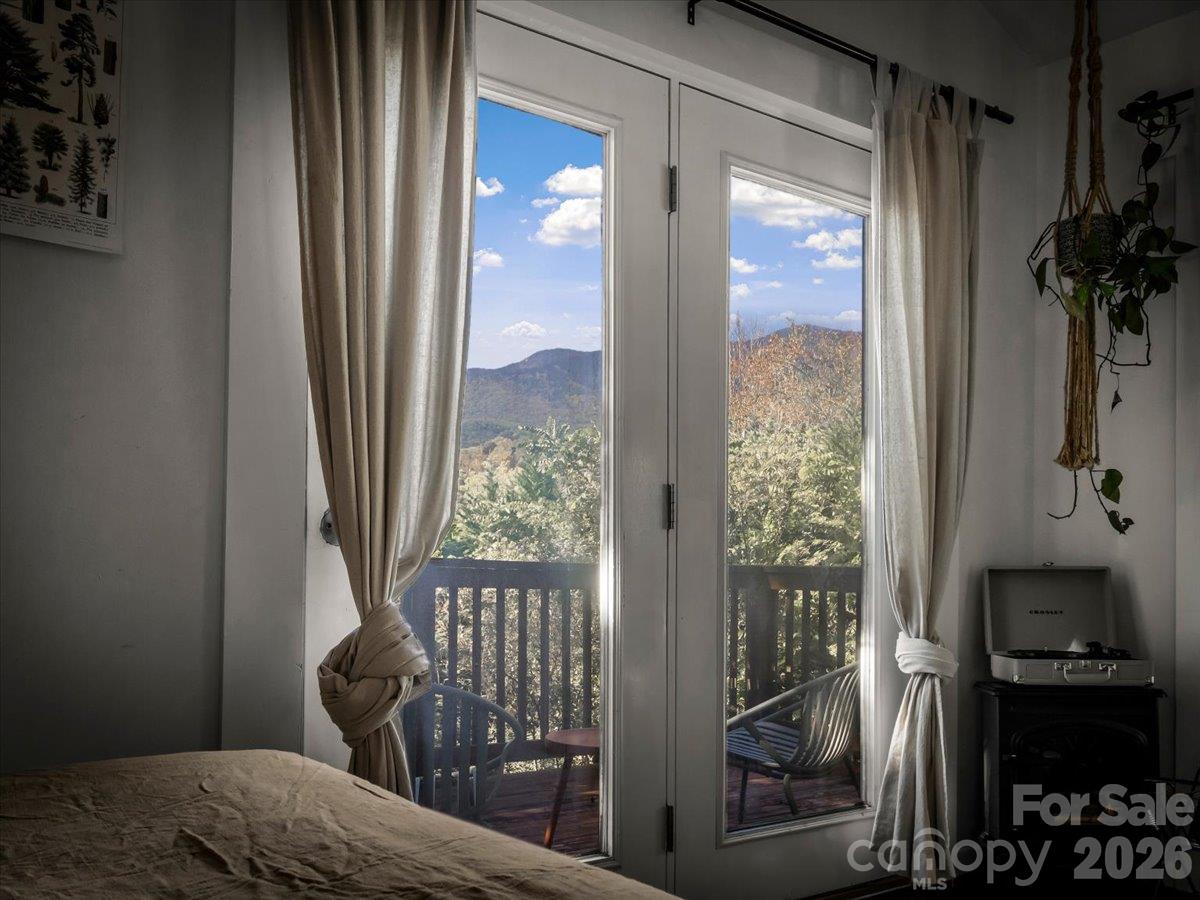 Bedroom with glass balcony doors framing a mountain view and autumn foliage.