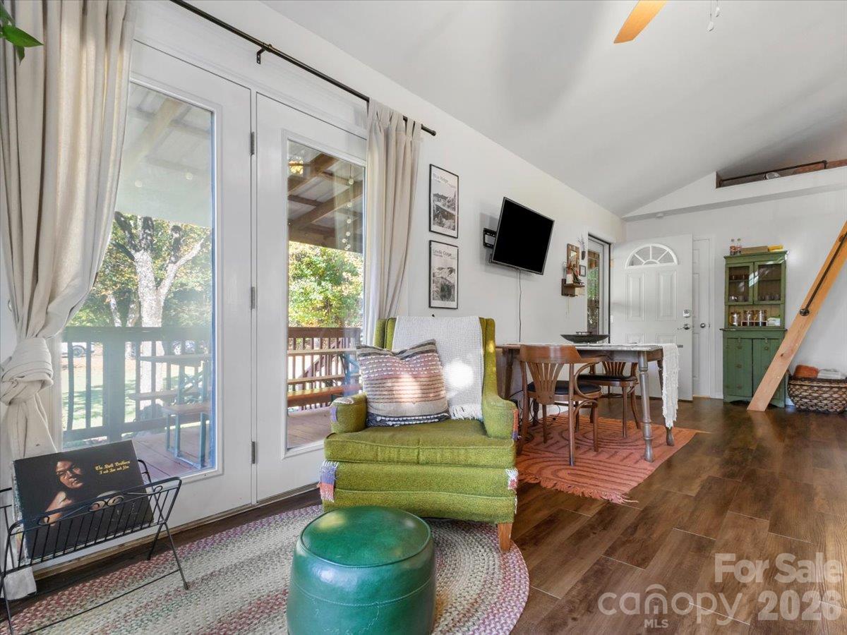 Living and dining area with a green armchair and glass doors opening onto a deck.