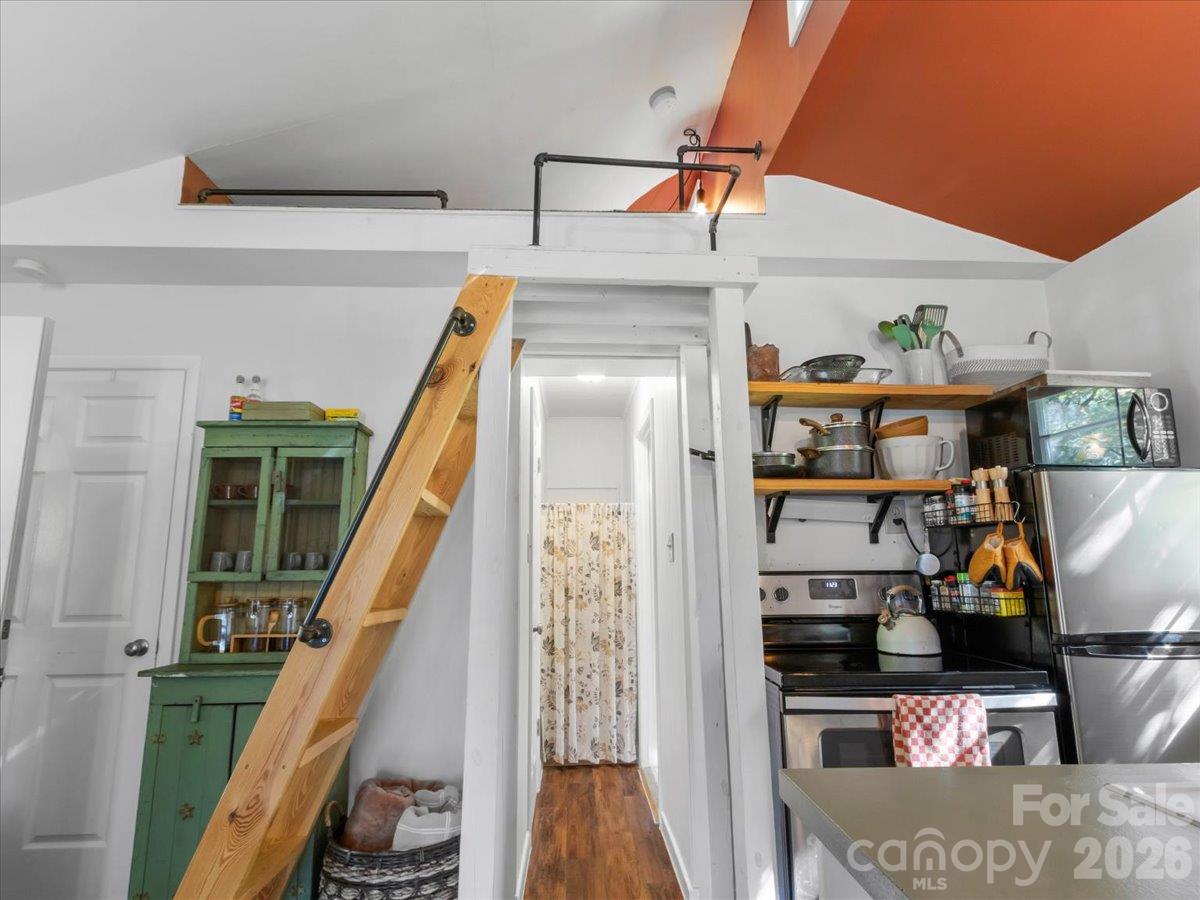 Compact kitchen with open shelves and a wooden ladder leading to a loft.
