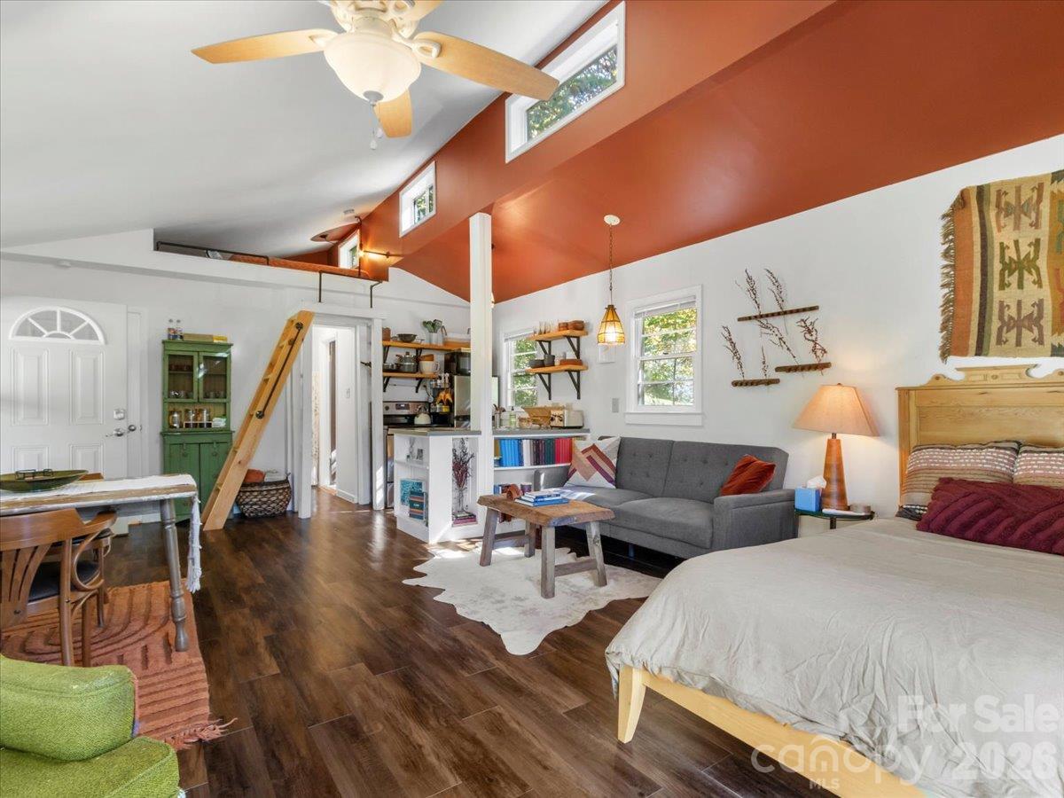 Open-plan room with a bedroom, living area, vaulted ceiling and ladder to a loft.