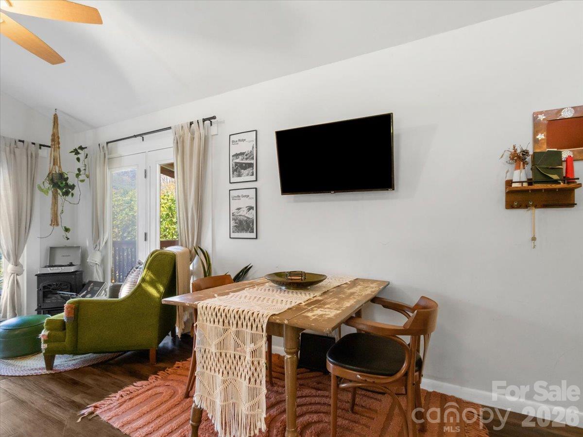 Dining and living area with a rustic table, green armchair, and glass doors to a balcony.