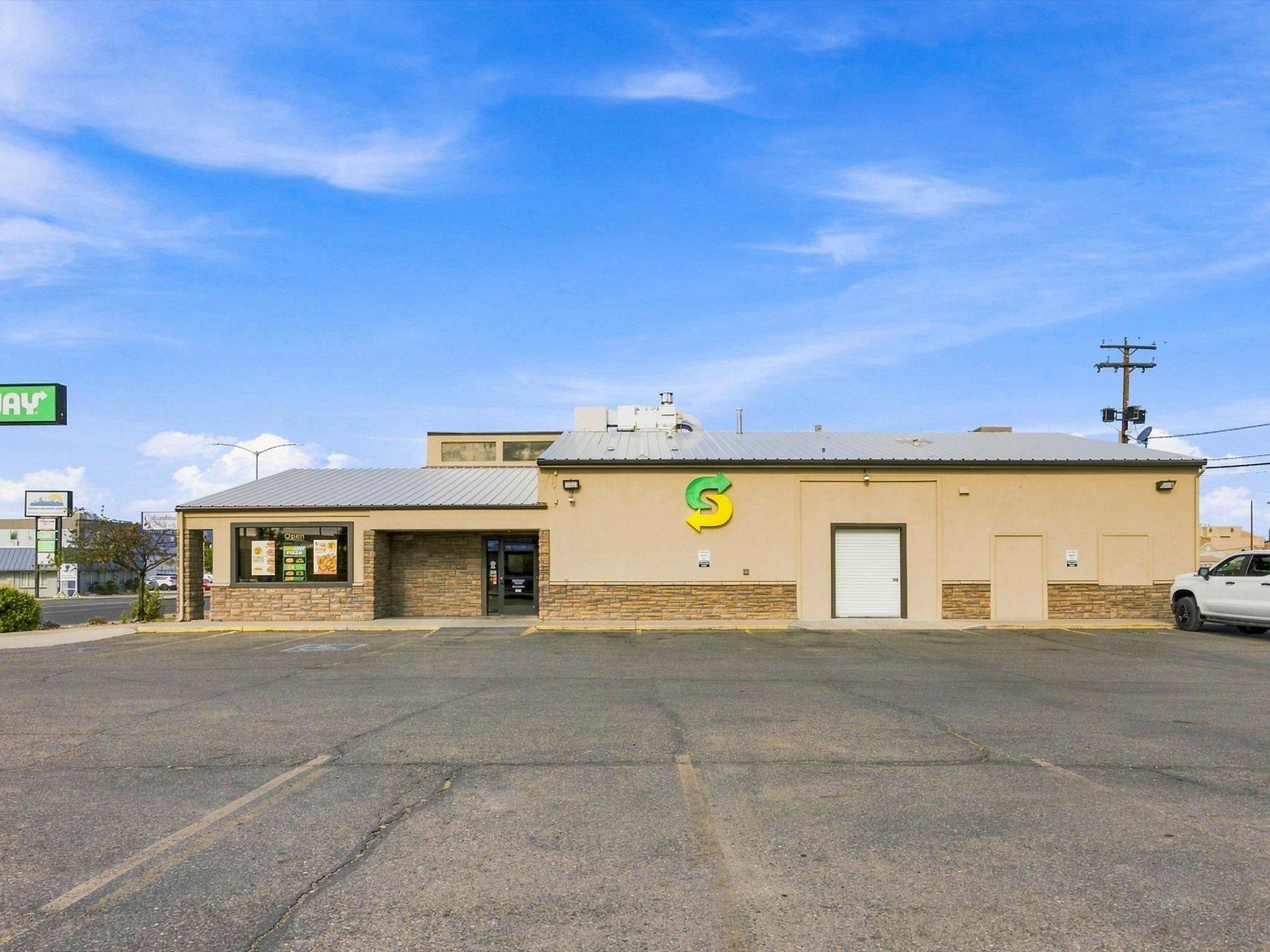 Beige commercial building with a Subway logo, stone veneer, and an open parking lot.