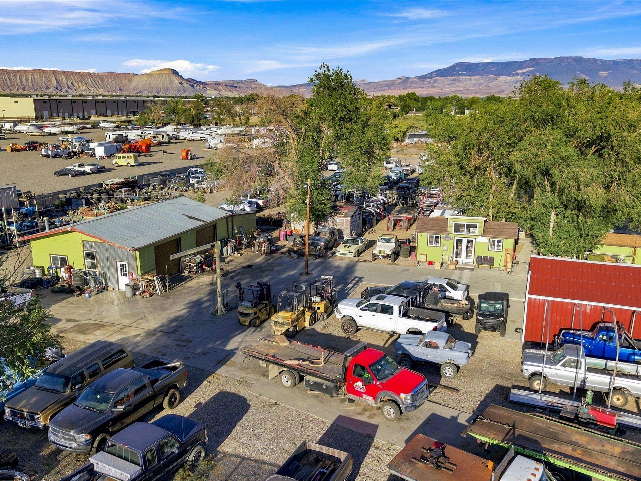 Industrial yard with parked trucks and workshops, backed by Grand Junction’s mesas and mountains.