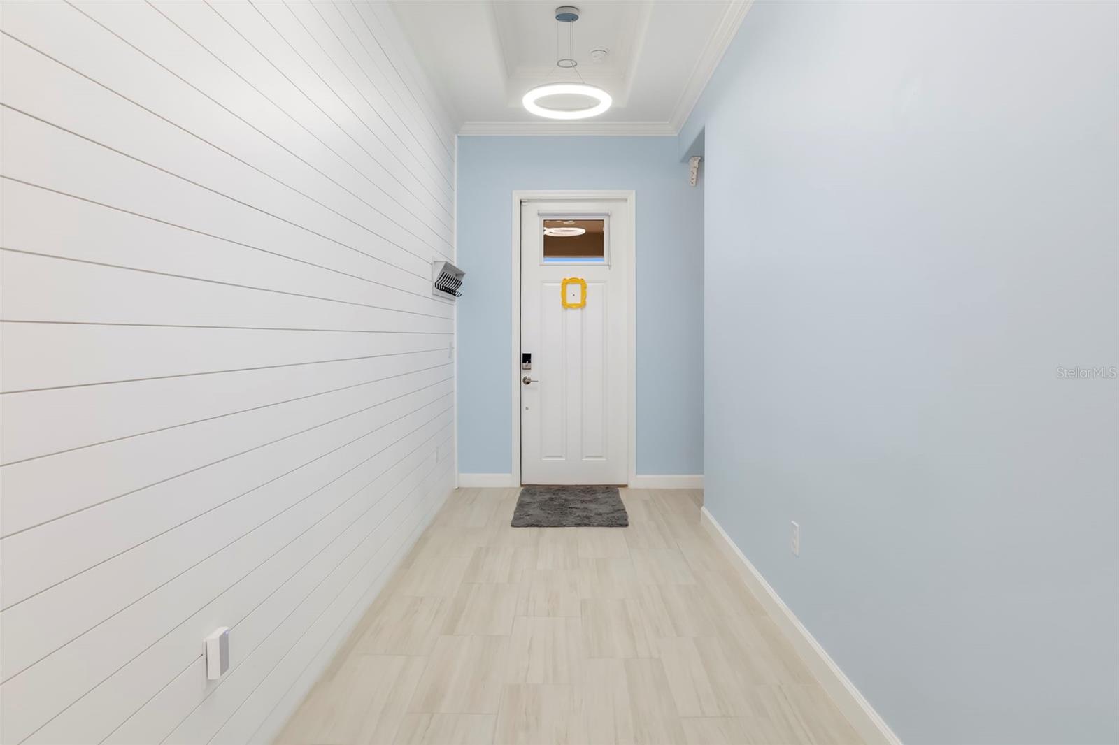 Entryway with white shiplap, pale blue walls, and a white front door.