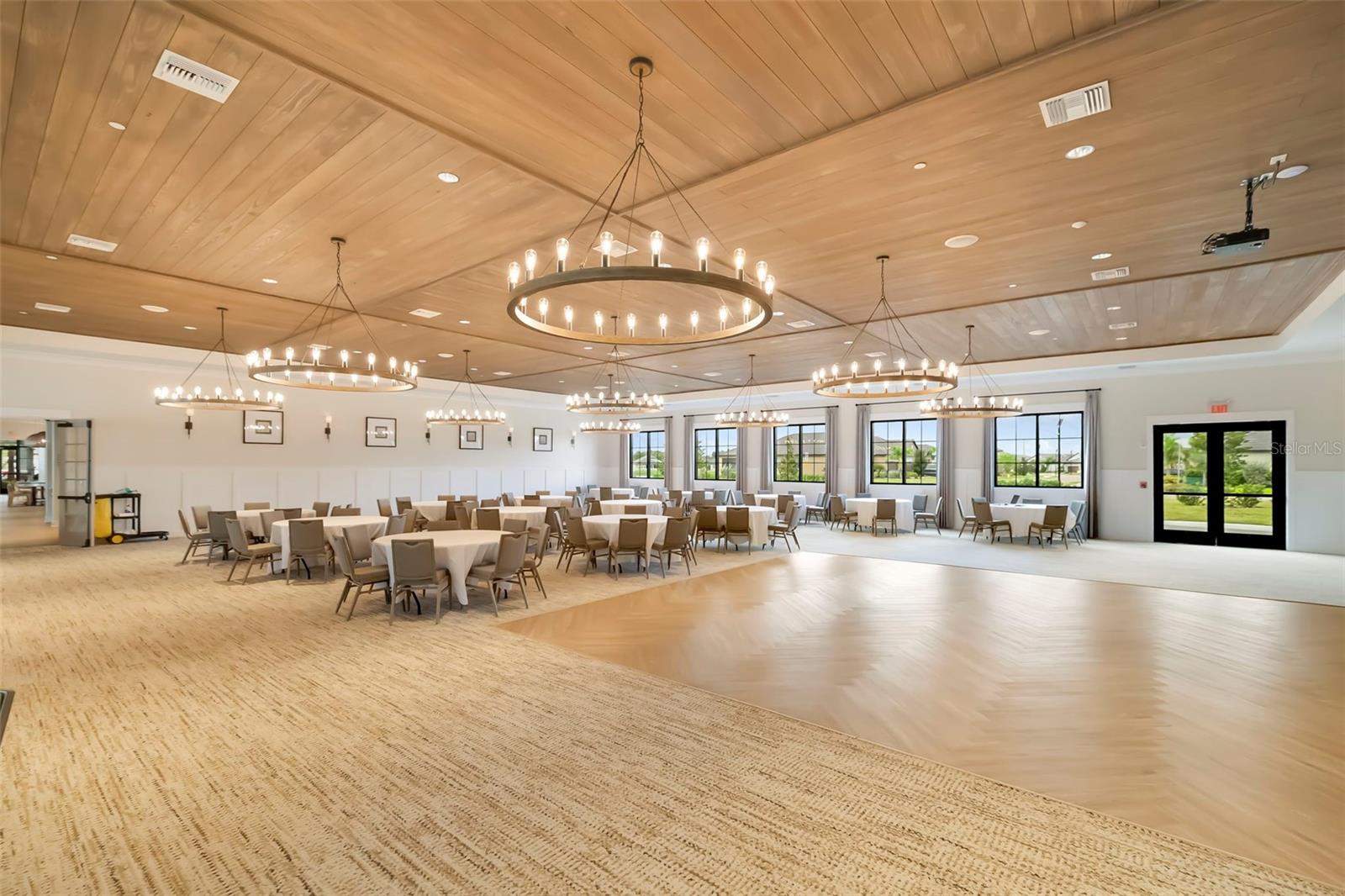 Community event room with banquet tables, circular chandeliers, and a wood dance floor.