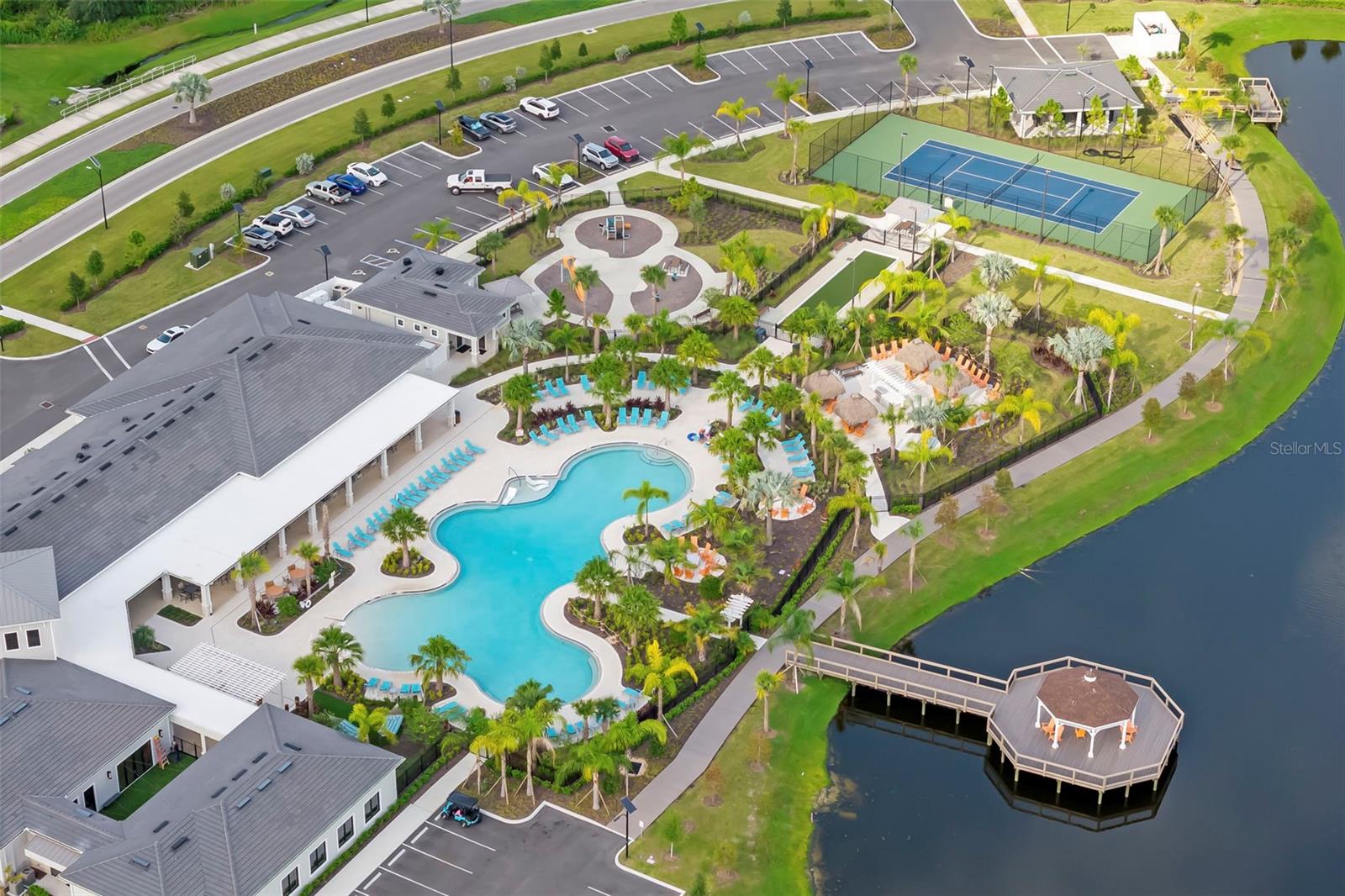 Community amenities with a curving pool, tennis court, and waterside gazebo.
