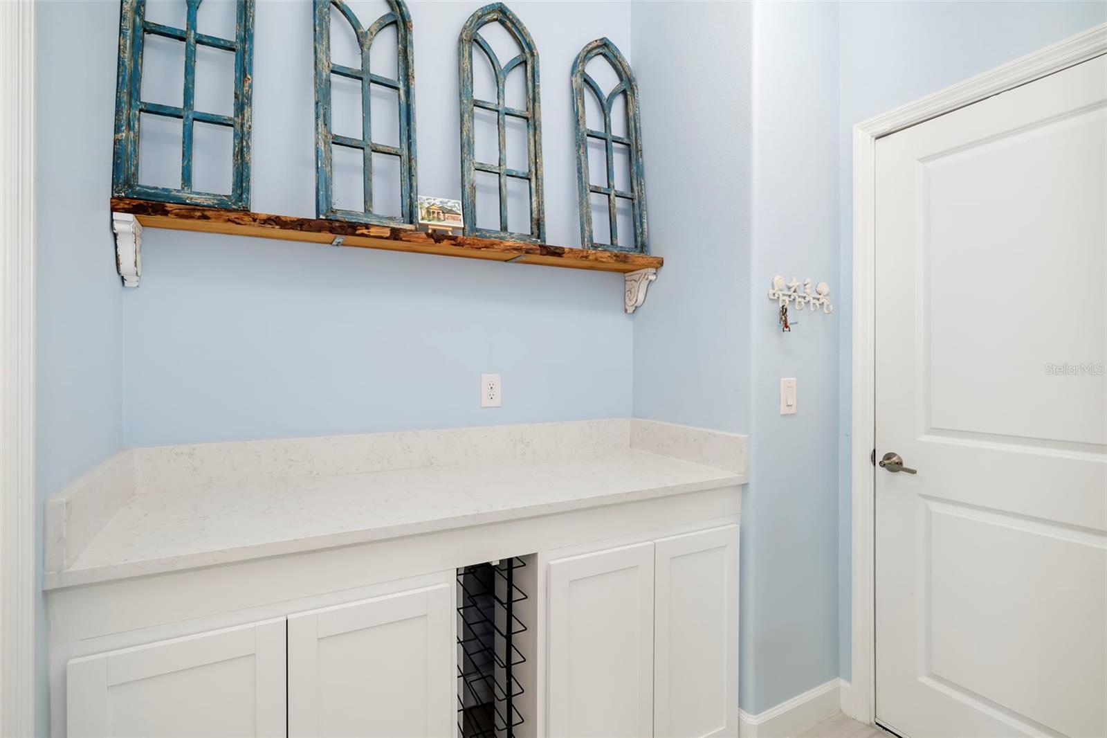 Built-in white counter and cabinets beneath distressed blue window-frame decor in a light blue room.
