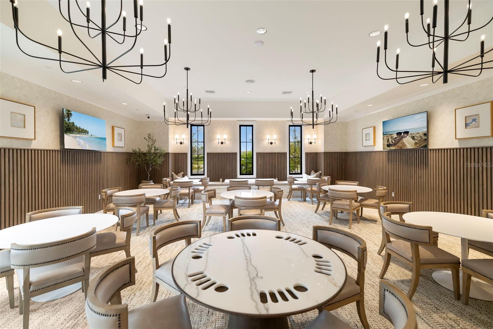 Furnished game room with poker tables, upholstered chairs, and oversized black chandeliers.
