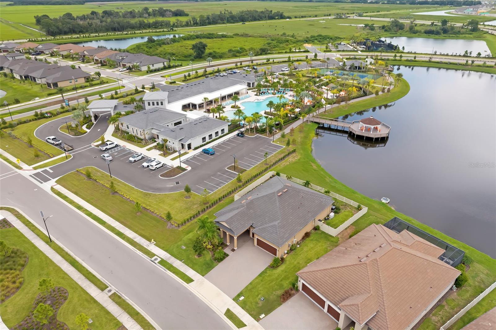 Aerial view of a neighborhood clubhouse, swimming pool, and surrounding ponds.