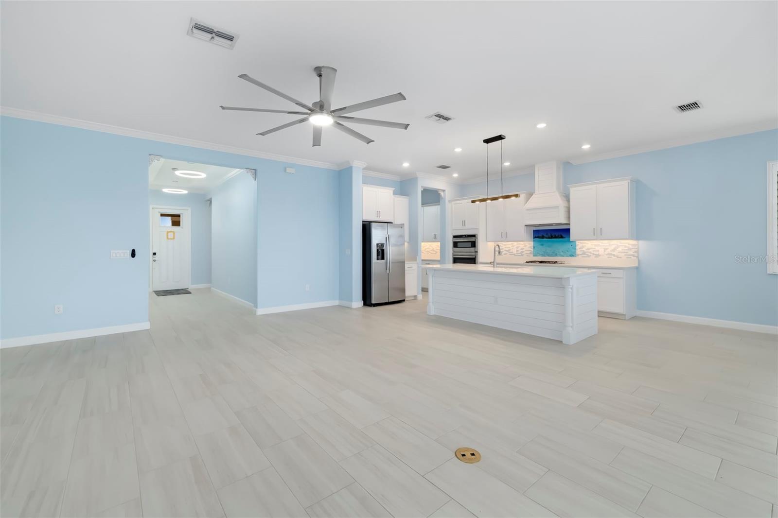Open kitchen with white cabinets, a large island, stainless steel appliances, and pale blue walls.