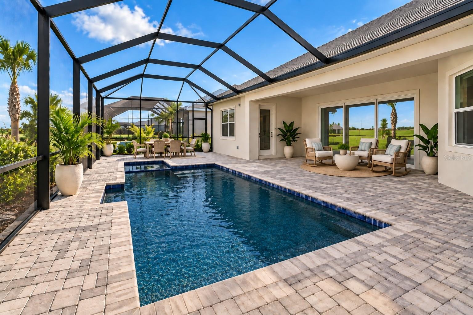 Screened pool patio with pale paver decking, lounge seating, and a dining set.