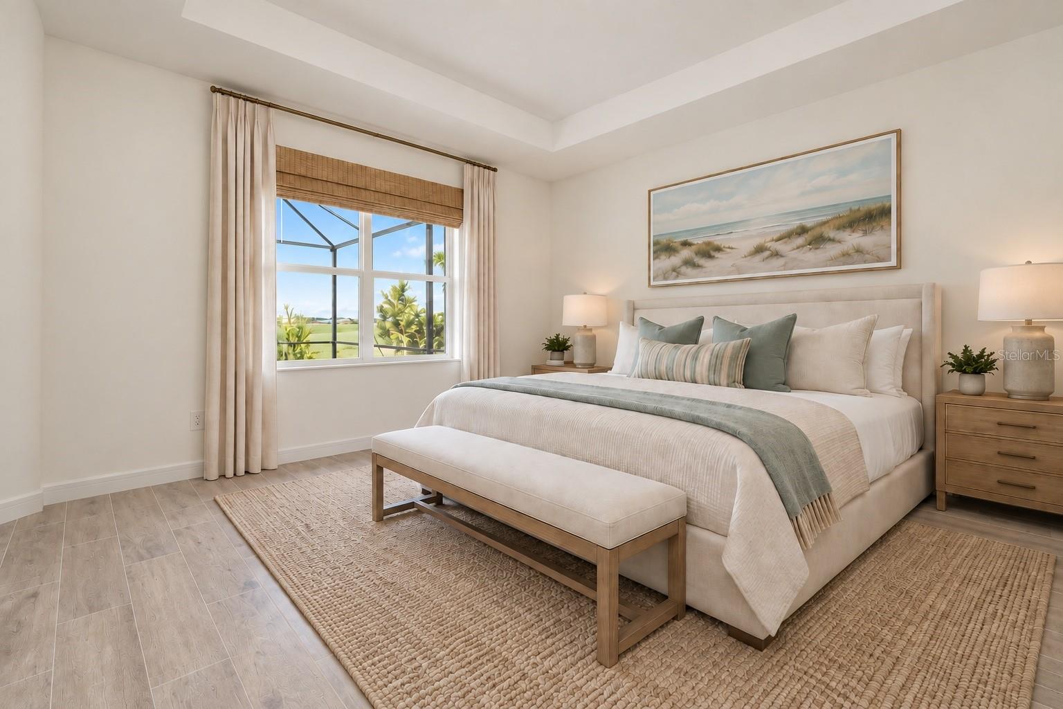 Staged bedroom with a neutral upholstered bed, woven rug, and wide window overlooking palms and lawn.