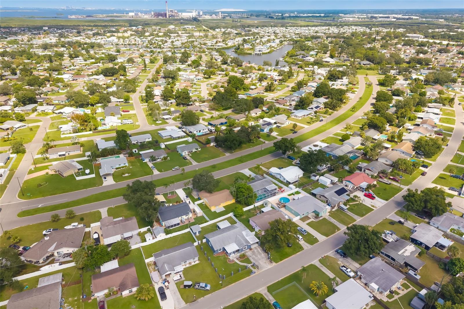 Aerial view of a residential neighborhood with canals and coastal water in the distance.